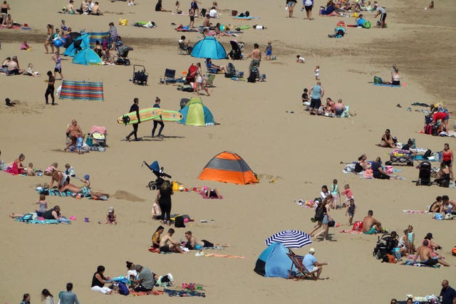 People enjoy the sunshine on Tynemouth beach (Owen Humphreys/PA)