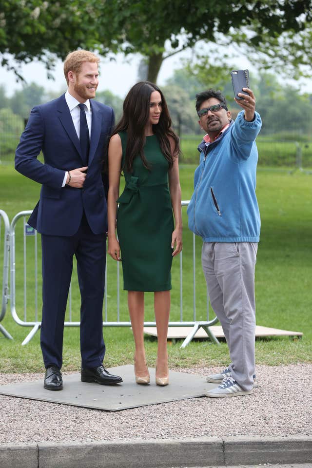 A royal fan takes a selfie with the Madame Tussauds' figures of Harry and Meghan along the Long Walk in Windsor (Jonathan Brady/PA)
