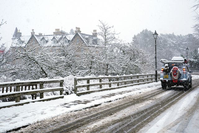 A car drives through snow in the Scottish Highlands