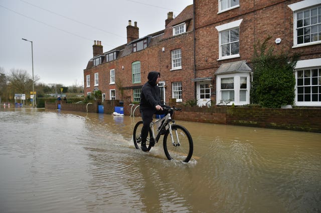 A cyclist negotiates the flood water in Tewkesbury (Ben Birchall/PA).