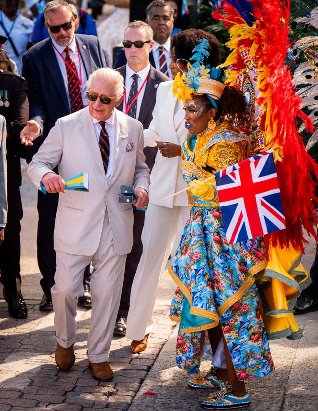The King with a performer during the celebratory Junkanoo street parade during a visit to Parliament Square, Nassau