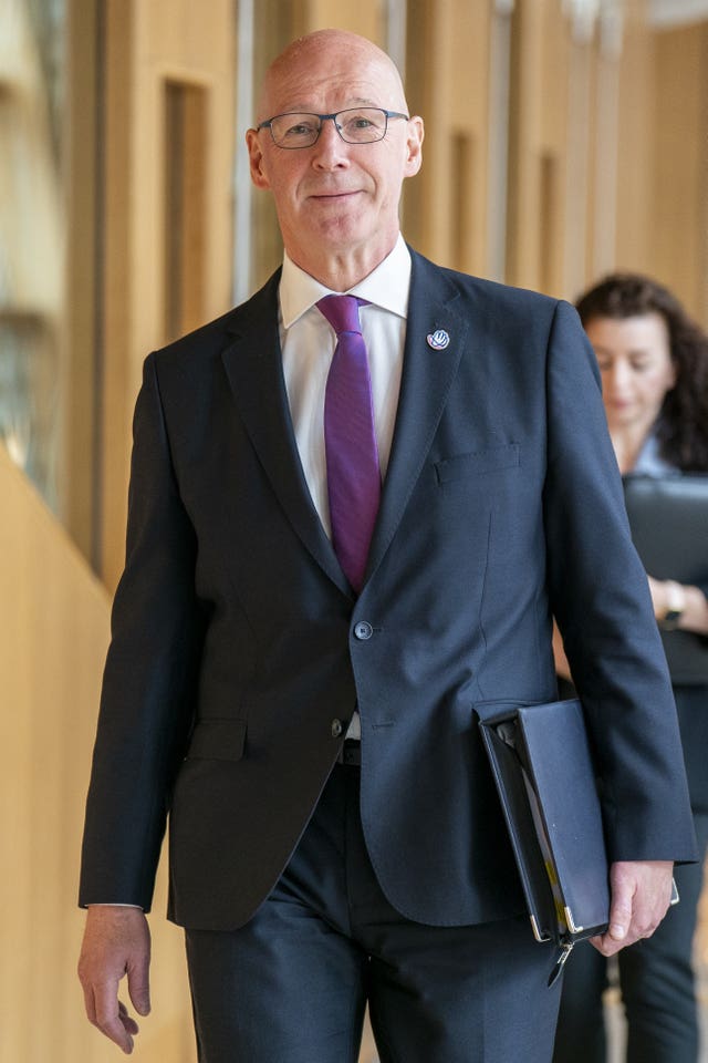 John Swinney in suit walking through corridor at Holyrood