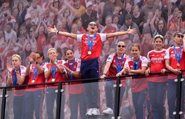 Katie McCabe stands with her arms out wide in celebration at Arsenal's victory parade