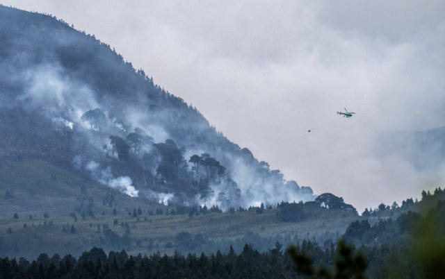 A helicopter carrying water tackles the wildfire burning near Nethy Bridge in Cairngorms National Park in north-east Scotland