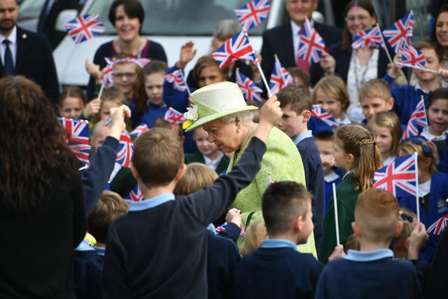 Schoolchildren waves flags to greet the Queen