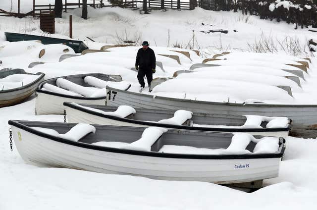Jimmy Feeney from the Carron Valley Fishery inspects his snow covered boats near Stirling, following the recent severe weather (Andrew Milligan/PA)