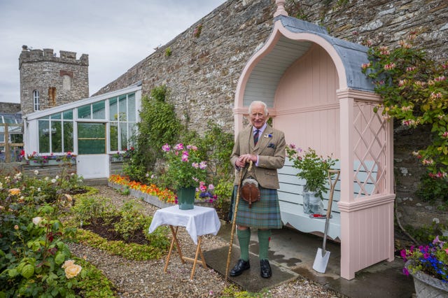 The King smiling while posing for photos in the walled garden of a castle