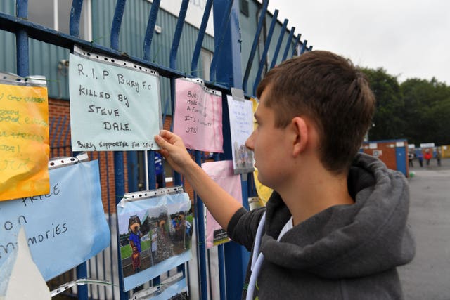 Messages from supporters are placed on a fence outside Bury's Gigg Lane stadium
