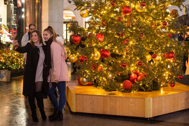 Shoppers take a photo infront of a Christmas tree on New Bond Street in central London