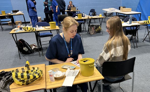 A student receives a vaccination in a large hall