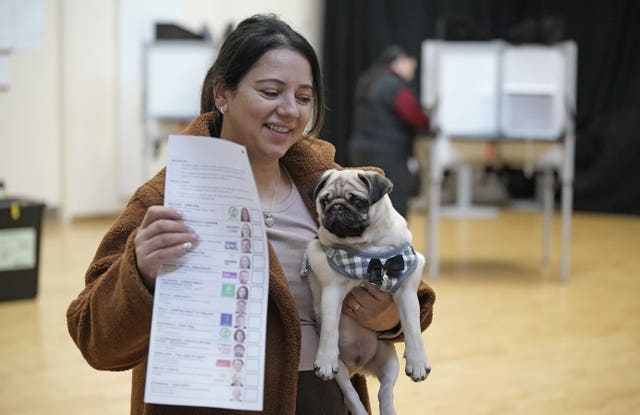 A woman holds a dog as she casts her vote at Deaf Village Ireland in Dublin