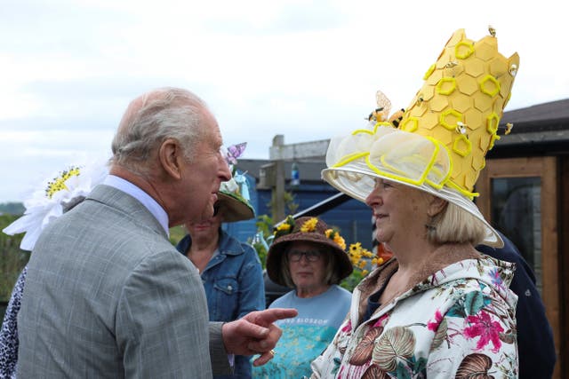The King chatting to allotment users dressed in floral design hats