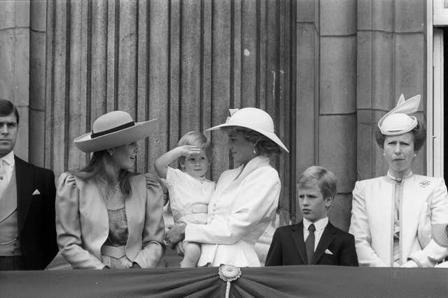 Prince Harry, in the arms of his mother the Princess of Wales, gives a salute on the palace balcony while watching the Queen's Guards march past (Ron Bell/PA)