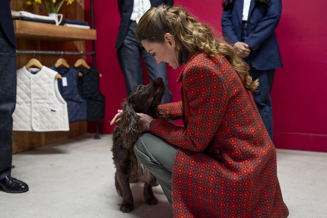 The Princess of Wales crouching down and stroking a cocker spaniel dog