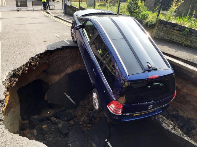 A car which has partially disappeared down a sinkhole in Woodland Terrace in Greenwich, south-east London