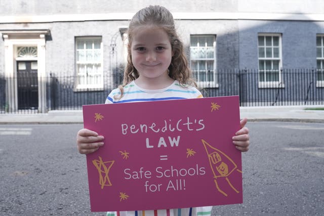 Etta Blythe holding a placard on Downing Street which reads 'Benedict's Law = Safe Schools For All'