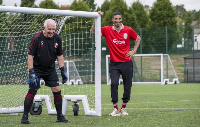 David James leans against a goalpost watching an elderly man in goal