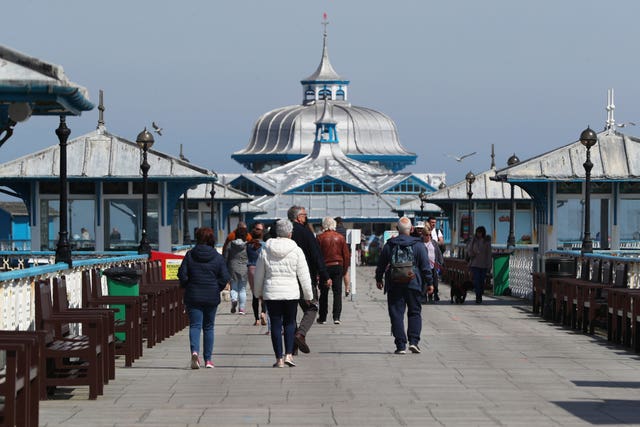 People walk along the pier in Llandudno, Wales, where lockdown restrictions have eased
