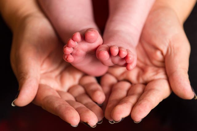A mother holds the feet of a new baby