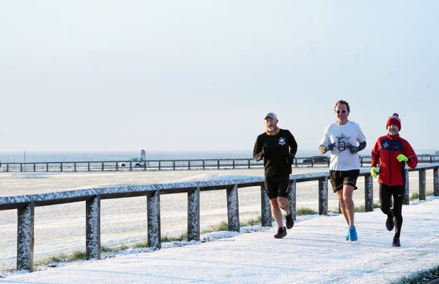 Runners were not deterred by the light snowfall on the North East coast (Owen Humphreys/PA)