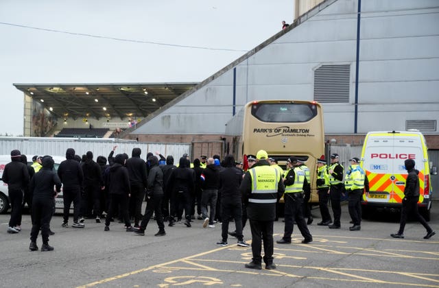 Police officers look on as Rangers fans try to stop the Rangers team bus leaving the Falkirk Stadium car park