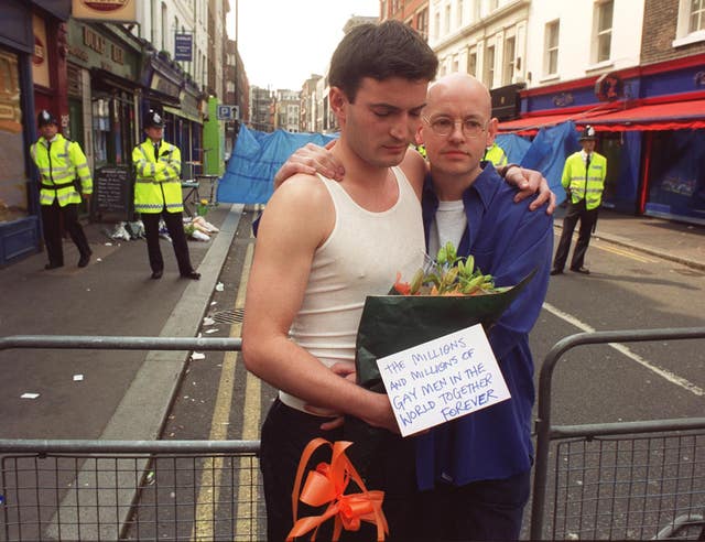 Two men arrive with a floral tribute at the scene of the bomb blast, in the centre of Soho, London. (PA).