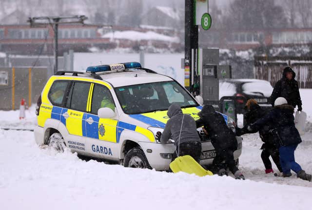 Members of the public help push a stuck garda police car in Jobstown, Tallaght, Dublin (Niall Carson/PA)