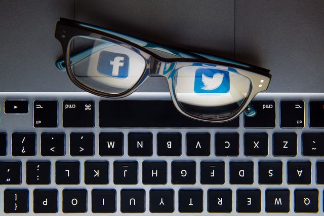 The logos of social network sites Facebook and Twitter reflected in a pair of glasses (Dominic Lipinski/PA)