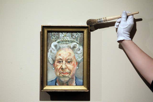 Curator Lauren Porter dusts a portrait by Lucian Freud, who declined an award, of the Queen (Steve Parsons/PA)