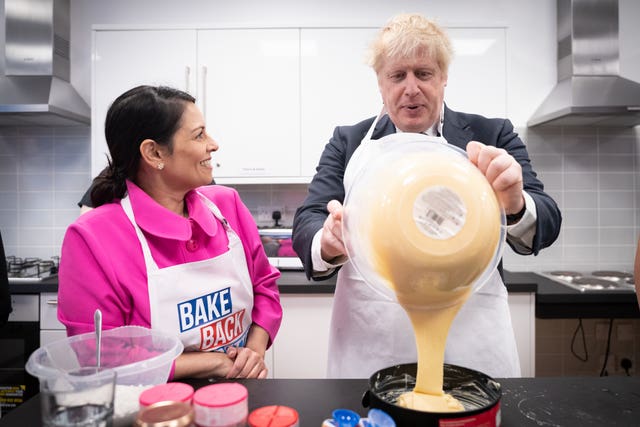 Home Secretary Priti Patel looks on as Prime Minister Boris Johnson tries his hand at baking during a visit to the HideOut Youth Zone, in Manchester