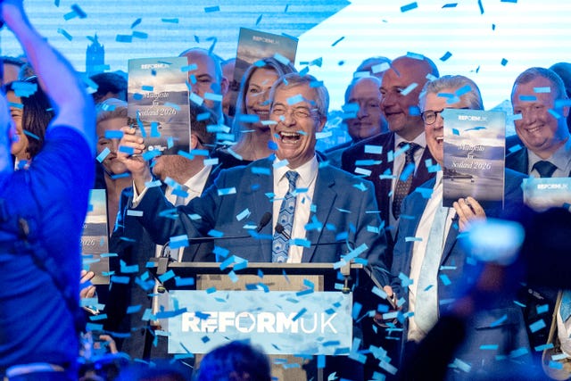 Nigel Farage and a host of Reform members smiling as confetti falls on them