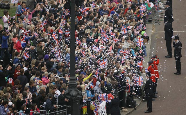 Confetti is thrown by the crowd gathered outside Buckingham Palace for the wedding of the Duke and Duchess of Cambridge at Westminster Abbey (David Bebber/PA)