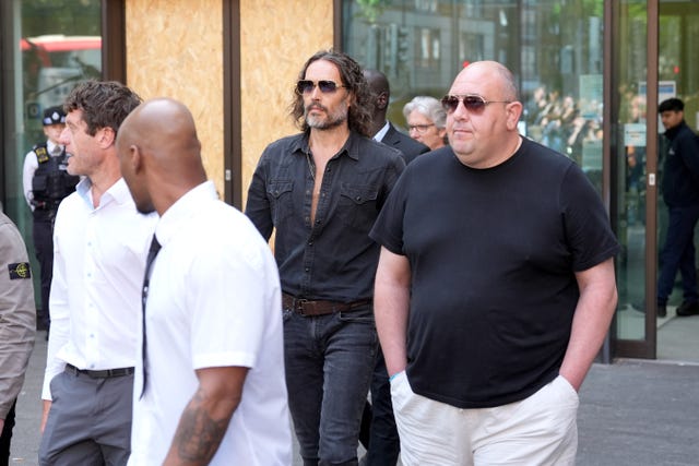 Russell Brand surrounded by people outside Westminster Magistrates’ Court