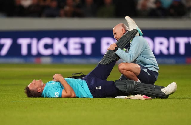 Jos Buttler receives treatment on his hamstring.