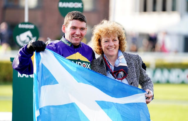 Derek Fox and trainer Lucinda Russell celebrate with a Scotland flag after Corach Rambler's success in the 2023 Grand National