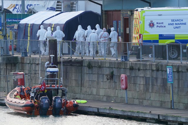 Police forensic officers head to the forensic tents erected at the RNLI station at the Port of Dover after a large search and rescue operation launched in the Channel off the coast of Dungeness in Kent, following an incident involving a small boat likely to have been carrying migrants in 2022