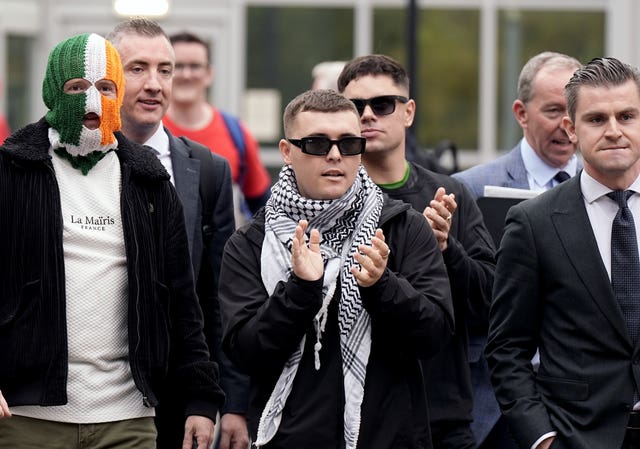 Kneecap’s Liam Og O hAnnaidh (centre, in keffiyeh), who performs under the stage name Mo Chara, with his lawyer Darragh Mackin and bandmates JJ O’Dochartaigh (left) and Naoise O Caireallain (back right) outside Woolwich Crown Court