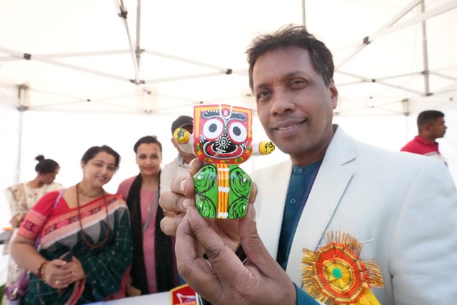 Event organizer Sanjeeb Barik with a statue of the Indian deity Jagannath as people attend the India Day Festival at Merrion Square Park, Dublin