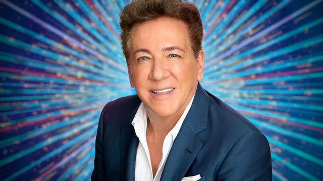 Headshot of Ross King smiling in front of a Strictly-themed background
