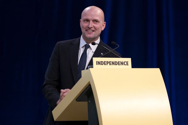 Stephen Flynn smiling while speaking from an SNP lectern