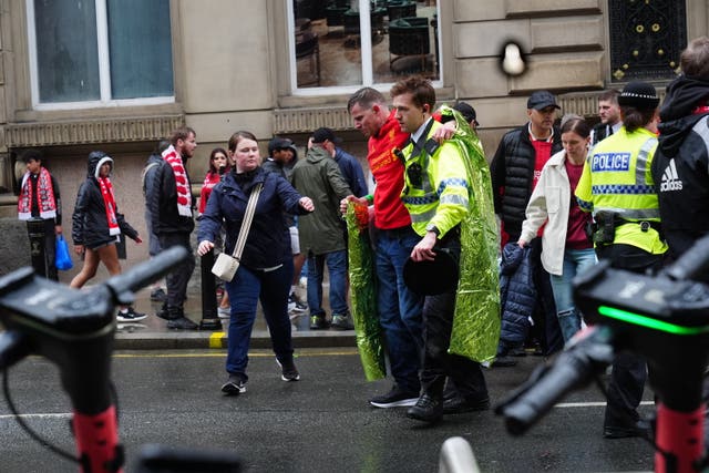 A police officer helps a man after a car crashed into a crowd during an incident in Liverpool