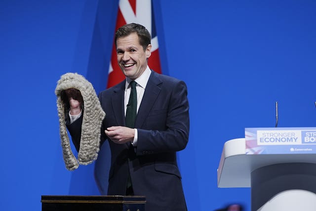 Robert Jenrick holds up a judge's wig during his speech to the 2025 Conservative party conference
