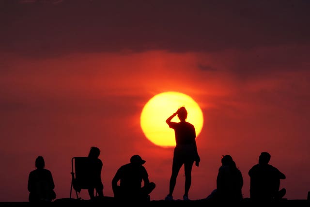 Someone superimposed over the rising sun with a red sky in the background