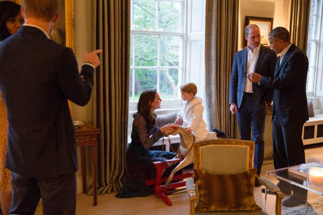 Barack Obama (right) talking with William while Kate plays with George as Michelle chats to Harry. Kensington Palace/Pete Souza/White House