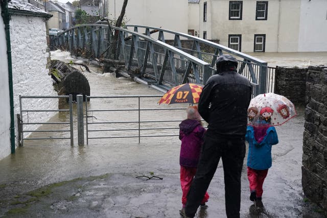 Brollies were out in force for those watching the rising water levels (Owen Humphreys/PA)