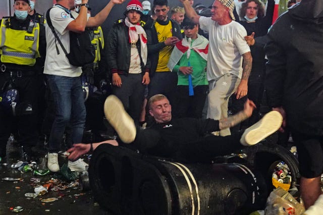 A football fan tumbles over a rubbish bin as they party in Piccadilly Circus, London