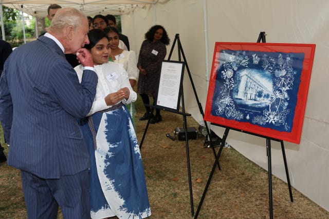 Charles speaks with Commonwealth student Ruwanthi Gajadeera as she presents him with a painting of the Victoria League headquarters