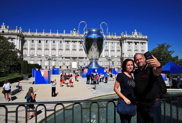 People take a photograph in front of a giant replica Champions League trophy at Plaza de Oriente in Madrid