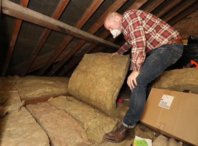 Richard Burr installing loft insulation (Philip Toscano/PA)