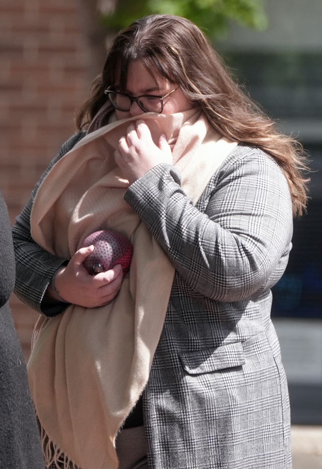 Kelsey Calvert in checked jacket with scarf held up to her face